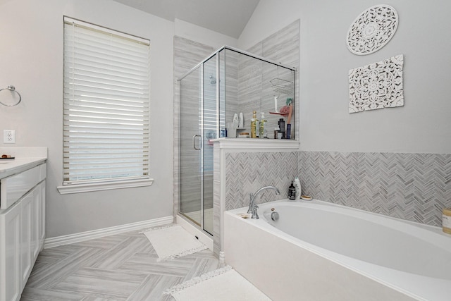 bathroom with baseboards, a garden tub, vaulted ceiling, vanity, and a shower stall