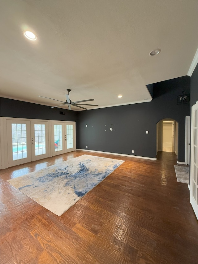 unfurnished living room featuring arched walkways, french doors, plenty of natural light, and wood finished floors