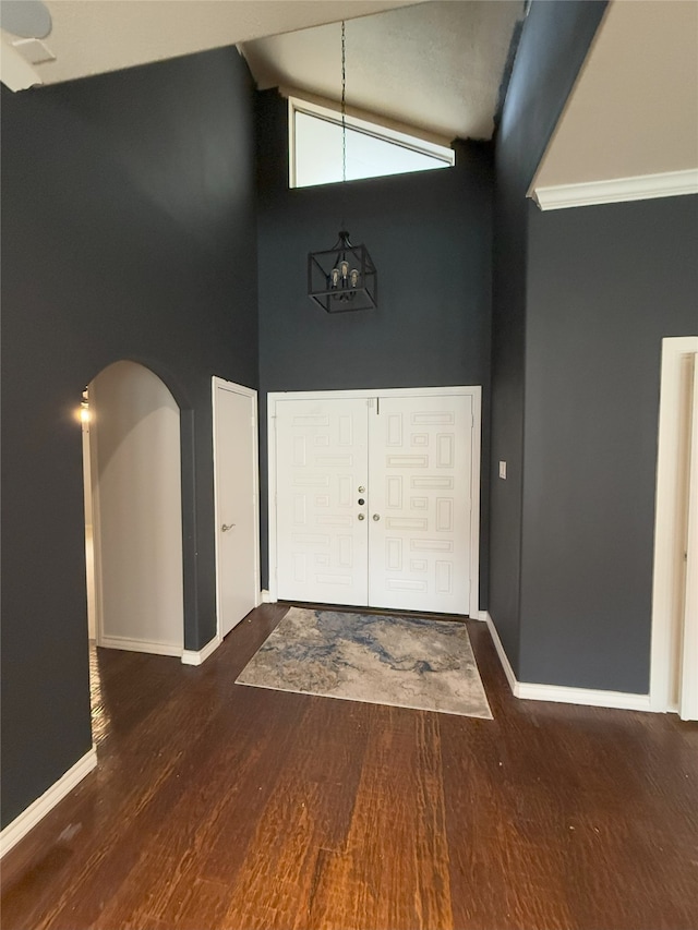 foyer entrance with arched walkways, high vaulted ceiling, baseboards, dark wood-style floors, and an inviting chandelier