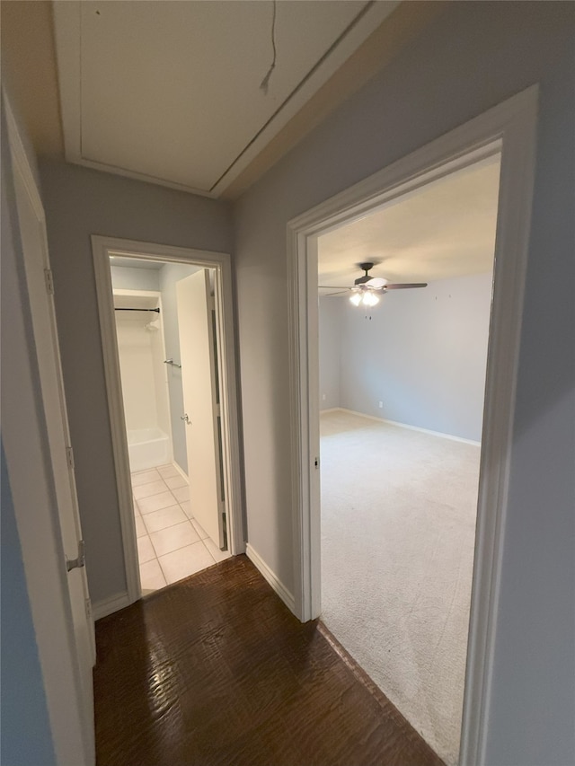 hall featuring attic access and baseboards