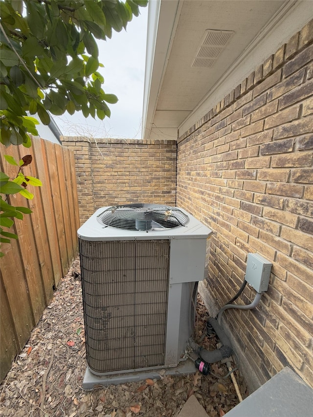 details featuring brick siding, fence, visible vents, and central air condition unit