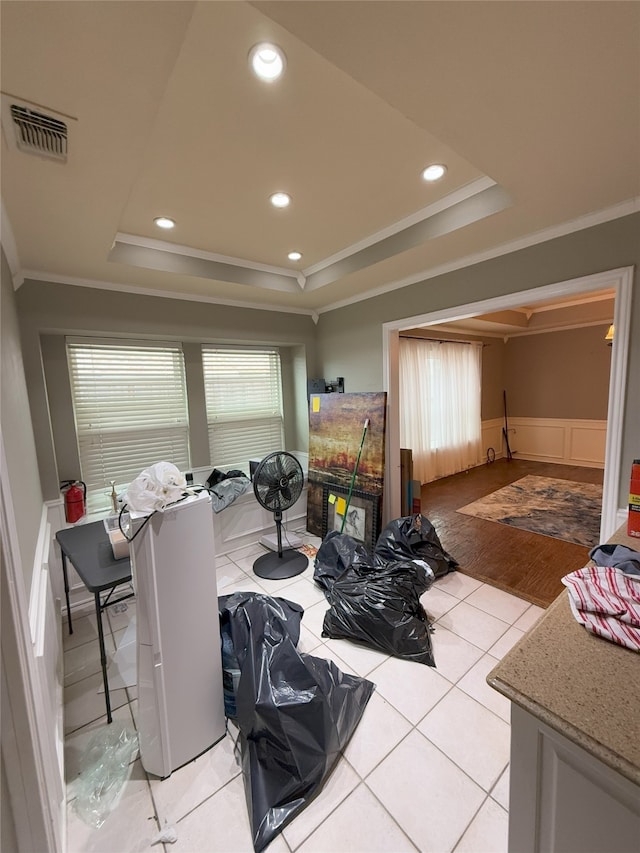 dining room with a raised ceiling, visible vents, a wainscoted wall, and a healthy amount of sunlight