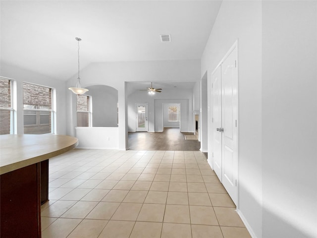 interior space with arched walkways, light tile patterned floors, visible vents, ceiling fan, and vaulted ceiling