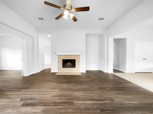 unfurnished living room featuring dark wood-type flooring, a tile fireplace, and visible vents