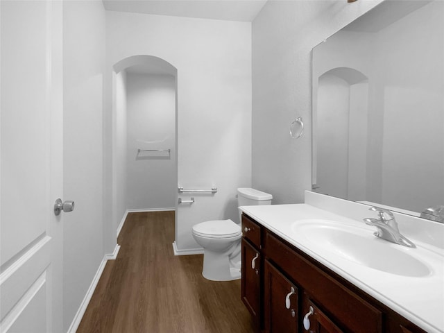 bathroom with vanity, wood finished floors, toilet, and baseboards