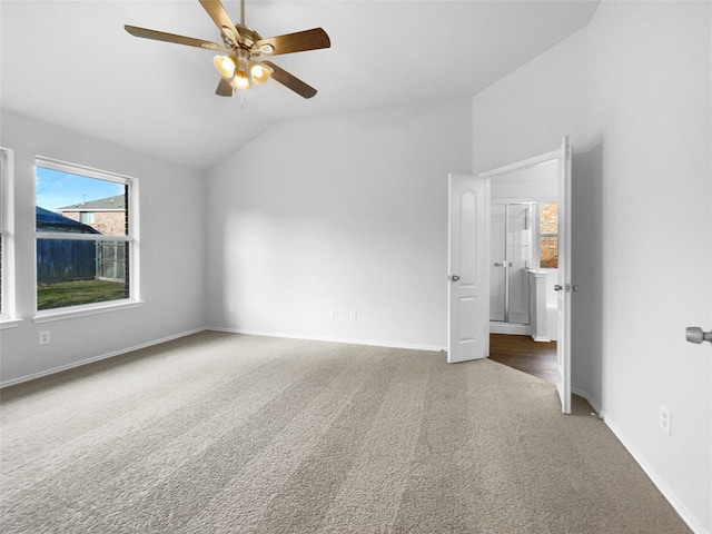 empty room featuring baseboards, dark carpet, vaulted ceiling, and a ceiling fan