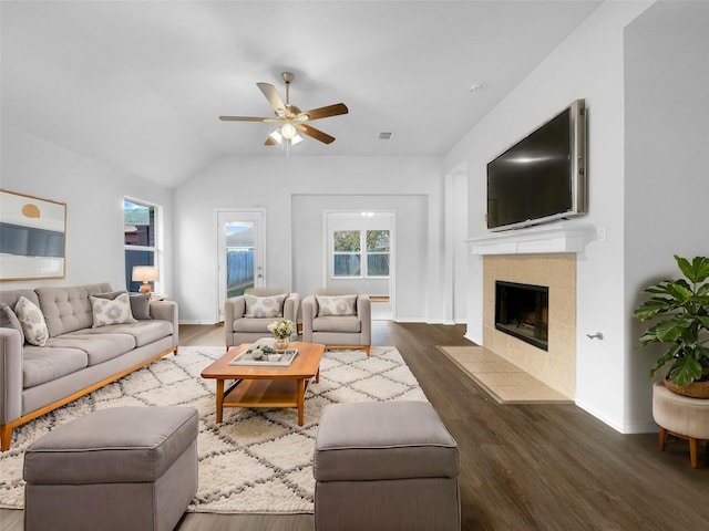 living area featuring lofted ceiling, a fireplace, visible vents, a ceiling fan, and dark wood finished floors