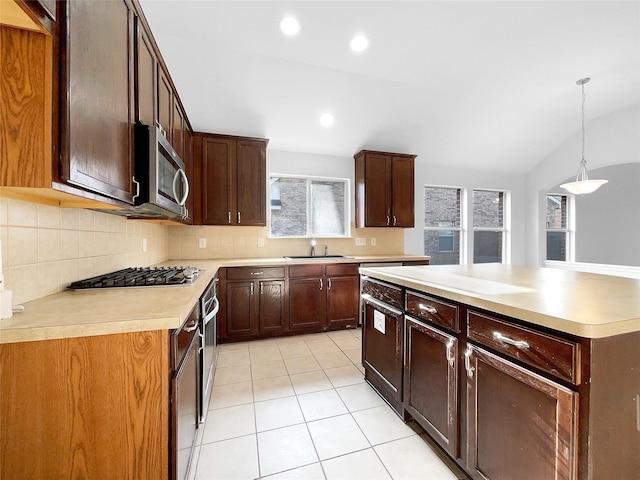 kitchen with stainless steel appliances, light countertops, a sink, and hanging light fixtures