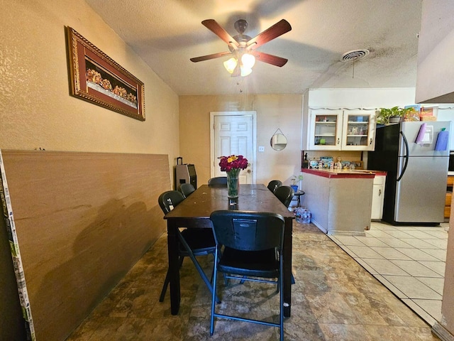 dining area with a ceiling fan, visible vents, and a textured ceiling