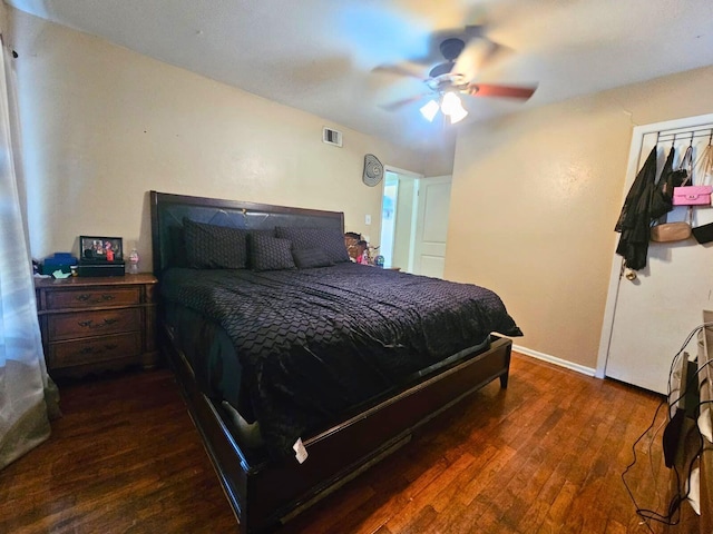 bedroom with a ceiling fan, dark wood-style flooring, visible vents, and baseboards