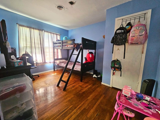 bedroom with dark wood finished floors, visible vents, and baseboards