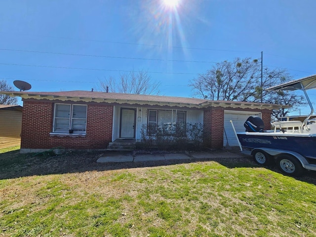 view of front facade with an attached garage, a front yard, and brick siding