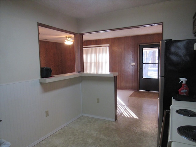 kitchen featuring wooden walls, light countertops, and electric range