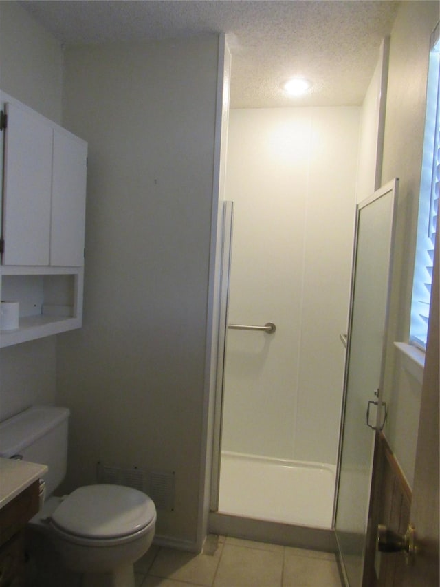 bathroom featuring toilet, tile patterned flooring, walk in shower, a textured ceiling, and vanity