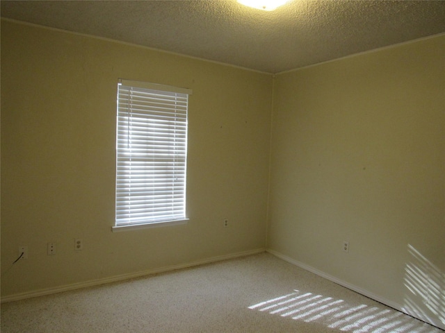 carpeted spare room featuring a textured ceiling and baseboards