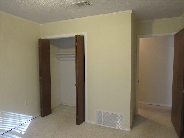 unfurnished bedroom with light carpet, a closet, visible vents, and a textured ceiling