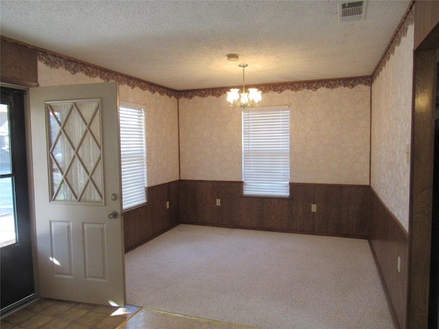 interior space with visible vents, wainscoting, carpet flooring, a textured ceiling, and a notable chandelier