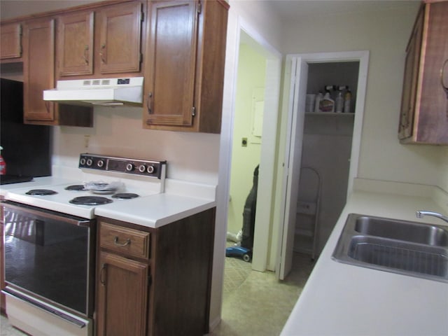 kitchen featuring brown cabinets, white electric stove, light countertops, a sink, and under cabinet range hood