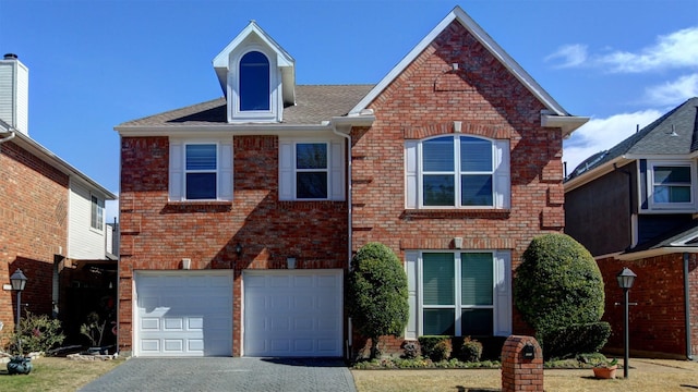 traditional-style house featuring driveway, brick siding, and an attached garage