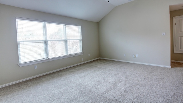 empty room featuring lofted ceiling, carpet floors, and baseboards