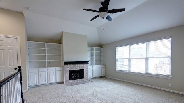 unfurnished living room with ceiling fan, light colored carpet, baseboards, vaulted ceiling, and a tiled fireplace