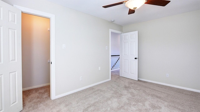 unfurnished bedroom with a ceiling fan, light colored carpet, and baseboards