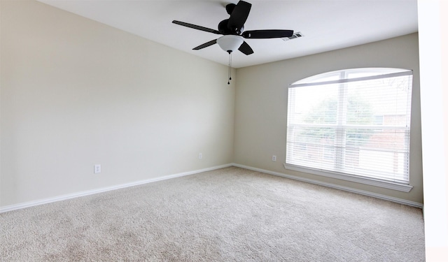 carpeted spare room featuring a ceiling fan, visible vents, and baseboards