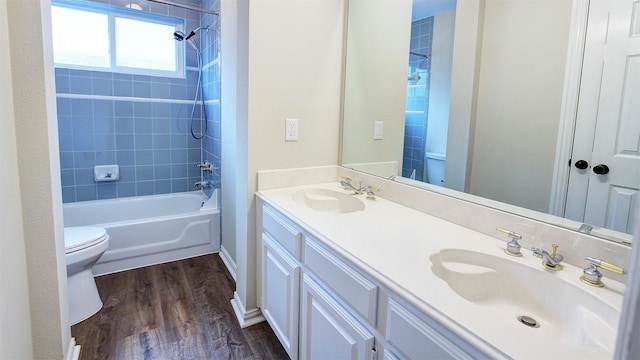 bathroom featuring toilet, bathing tub / shower combination, a sink, and wood finished floors