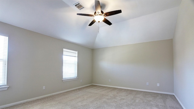 empty room with light carpet, baseboards, visible vents, a ceiling fan, and vaulted ceiling