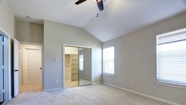 unfurnished bedroom featuring a closet, light colored carpet, a ceiling fan, vaulted ceiling, and baseboards