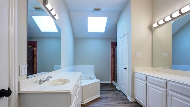 bathroom with a skylight, wood finished floors, vanity, and a bath