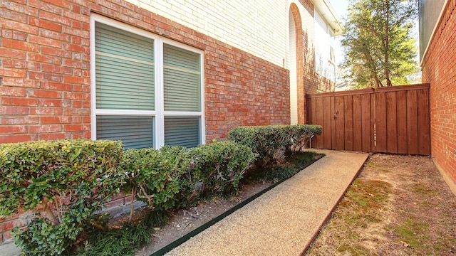 view of property exterior featuring brick siding and fence