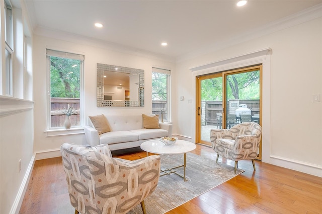 living area with light wood-style floors, baseboards, crown molding, and recessed lighting