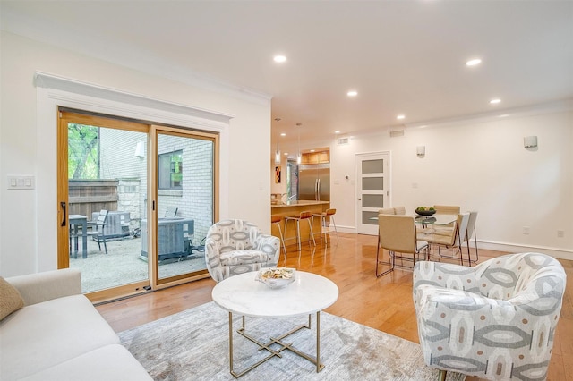 living room with light wood finished floors, baseboards, ornamental molding, and recessed lighting