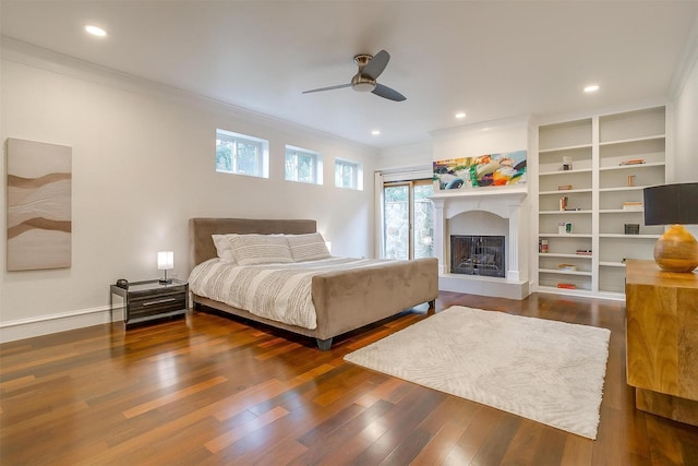 bedroom featuring a fireplace with raised hearth, a ceiling fan, dark wood-style floors, ornamental molding, and recessed lighting