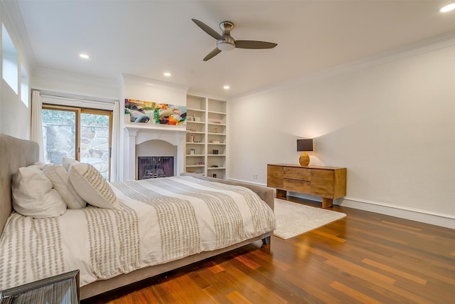 bedroom featuring recessed lighting, dark wood-type flooring, a fireplace, baseboards, and crown molding