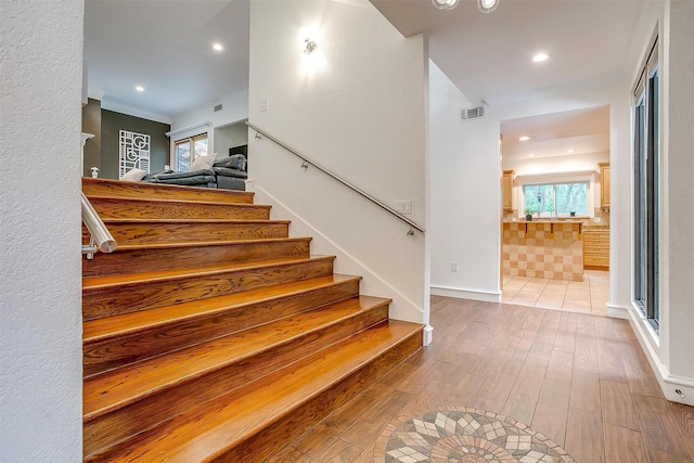 stairway featuring baseboards, visible vents, wood finished floors, and recessed lighting