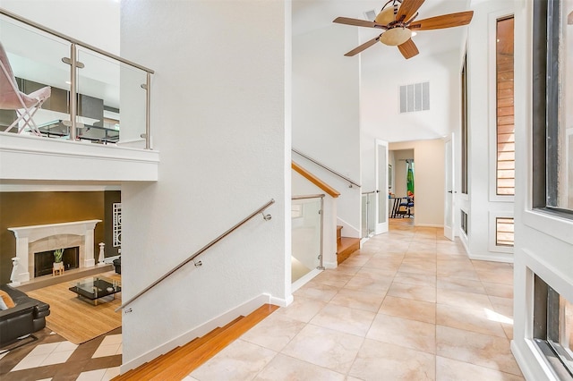 entryway with a fireplace, visible vents, baseboards, stairs, and a ceiling fan