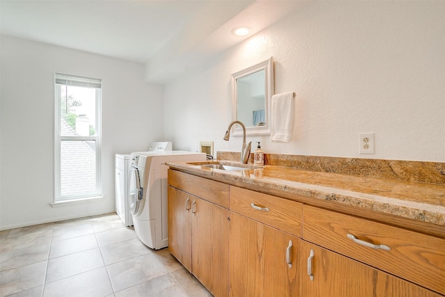 laundry area featuring light tile patterned floors, a sink, and washer and dryer