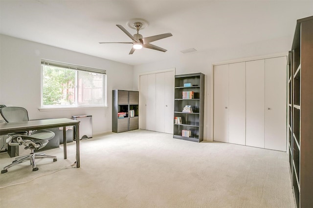 office space featuring a ceiling fan and light colored carpet