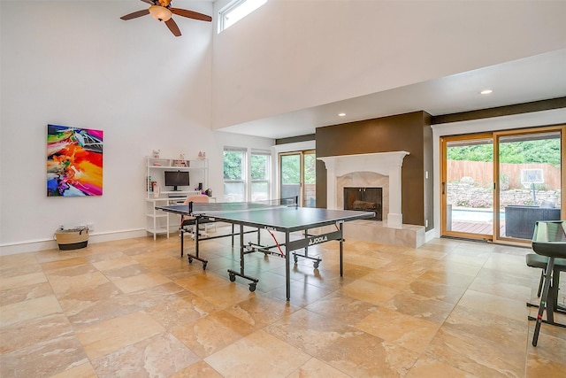 game room with a towering ceiling, plenty of natural light, a fireplace, and baseboards