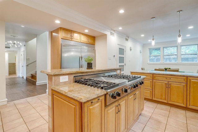 kitchen with appliances with stainless steel finishes, a center island, light stone countertops, pendant lighting, and light tile patterned flooring