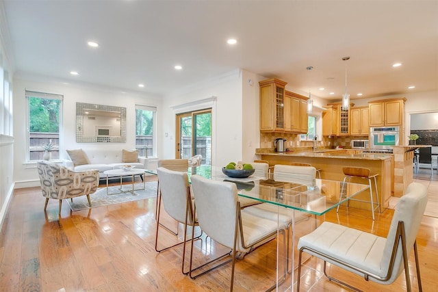 dining space with light wood-style floors, crown molding, and recessed lighting