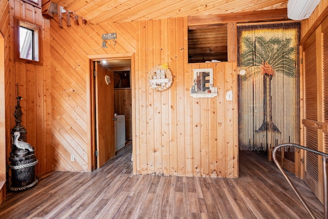 spare room featuring dark wood-style flooring, a wall mounted air conditioner, wooden ceiling, and wood walls