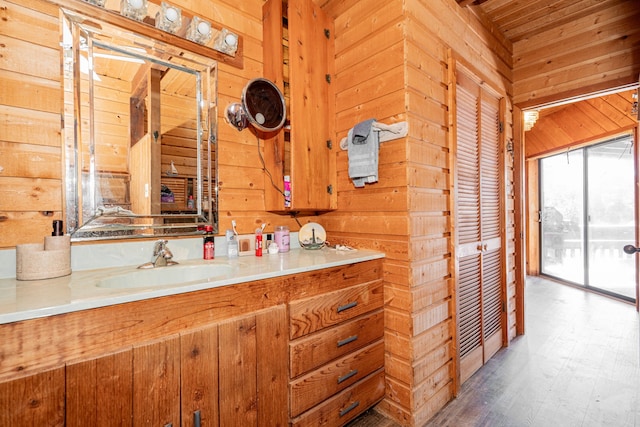 bathroom with wooden walls, wood finished floors, and vanity