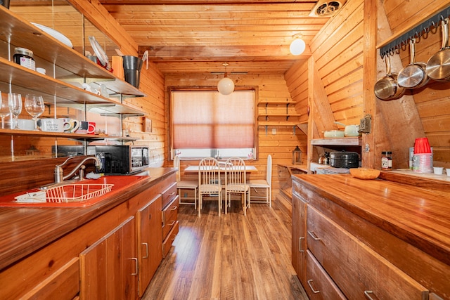 kitchen with brown cabinetry, wood ceiling, wooden walls, and wood finished floors