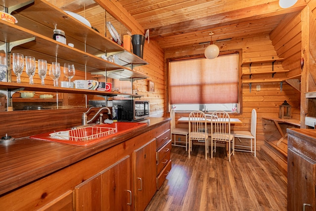 kitchen featuring wooden ceiling, wooden walls, a sink, hanging light fixtures, and dark wood-style floors