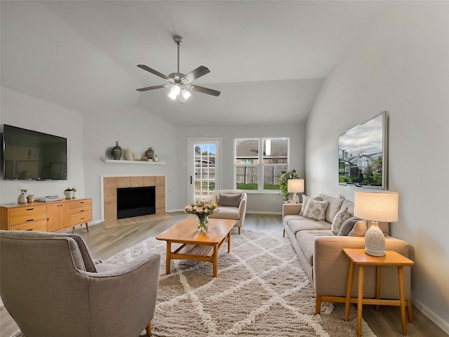 living room featuring vaulted ceiling, a fireplace, light wood finished floors, and ceiling fan