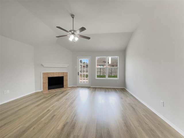 unfurnished living room featuring a tile fireplace, a ceiling fan, baseboards, vaulted ceiling, and light wood finished floors