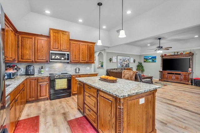 kitchen featuring electric range, a kitchen island, stainless steel microwave, open floor plan, and decorative light fixtures